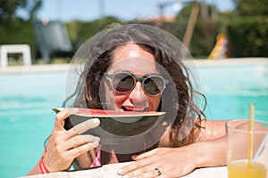 Pretty woman eating watermelon in pool