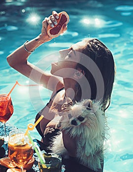 Pretty woman enjoying a fresh juice and cocktail in a swimming pool.