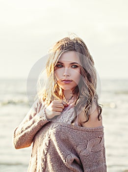 Pretty woman face. Beautiful model girl with long curly hair and clear skin on ocean coast