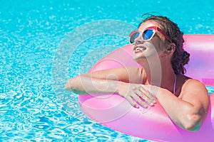 Pekná žena plávajúce ružový guma nafukovacie krúžok v plávanie bazén a zabávajúci sa 