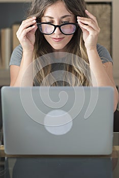 Pretty woman with glasses eyewear work at home on laptop computer - smart working female people at office desk looking the monitor