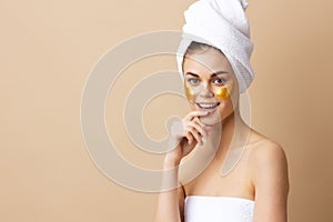 pretty woman golden patches on the face with a towel on the head beige background