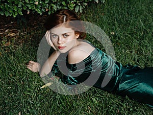 pretty woman in green dress lies on the grass in the fantasy garden