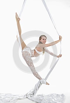 Pretty woman hanging in aerial silk - aerialist performing aerial tricks.