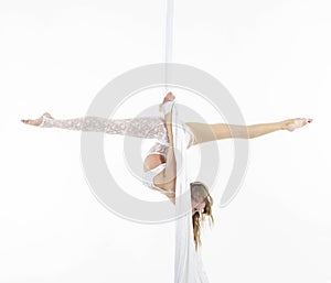Pretty woman hanging in aerial silk - aerialist performing aerial tricks.