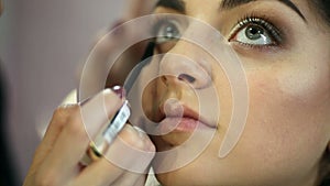 A pretty woman having make-up applied by a makeup