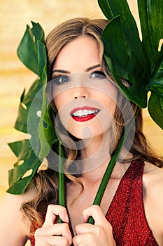 Pretty woman with healthy clear skin holding green leaves