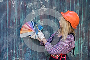 pretty woman in helmet and uniform ready for home repair, holding color palette