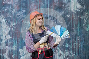 pretty woman in helmet and uniform ready for home repair, holding color palette