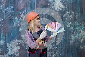 pretty woman in helmet and uniform ready for home repair, holding color palette