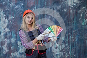 pretty woman in helmet and uniform ready for home repair, holding color palette