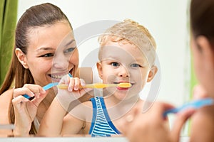 Pretty woman and her son brushing their teeth and looking at miroor in bathroom