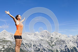 Pretty woman hiker standing on a rock with raised hands