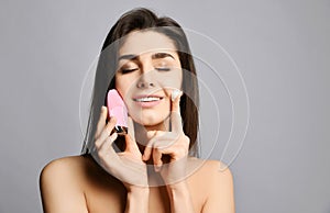 Pretty woman hold pink face exfoliator brush silicone cleansing device for sensitive normal skin and cream. She relishes softness