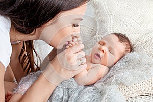 Pretty woman holding a newborn baby in her arms. Happy mother and her slipping newborn baby in the bed