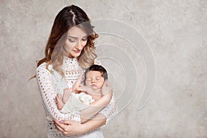 Pretty woman holding a newborn baby in her arms. Portrait of mother and little baby. Copy space