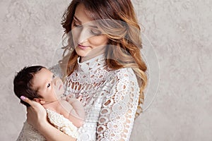 Pretty woman holding a newborn baby in her arms. Portrait of mother and little baby. Copy space