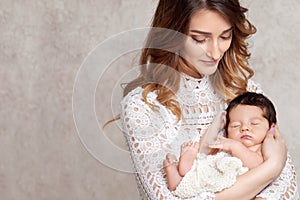 Pretty woman holding a newborn baby in her arms. Portrait of mother and little baby. Copy space