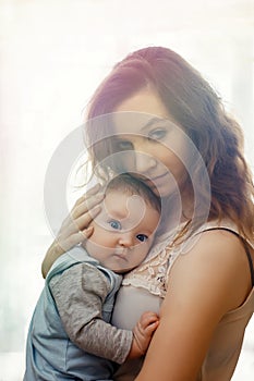 Pretty woman holding a newborn baby in her arms, sunlight, sunset