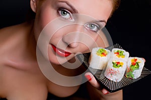 Pretty woman is holding a plate with japanese food