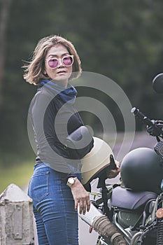 pretty woman holding safety helmet standing beside small enduro motorcycle