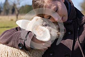 Pretty woman hugging intimately a little lamb