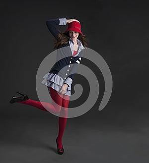 Pretty woman kicking up heels in fun fashion outfit in studio