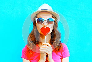 Pretty woman kissing red lollipop shape of a heart