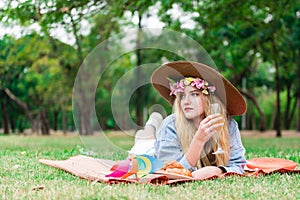 Pretty woman laying down on the grass with drinking a juice