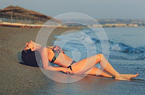 Pretty woman laying on wet sand at the beach