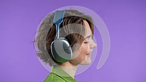 Pretty woman listening music, gets high,enjoying dance with headphones on violet
