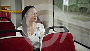 Pretty woman listening music in headphones on smartphone riding train, beautifull girl rides a city bus