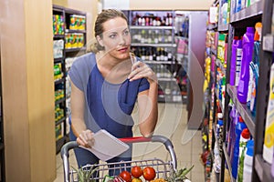 Pretty woman looking at product on shelf and holding grocery list