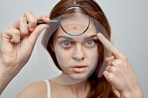 pretty woman with loose hair skin problems magnifier in hands