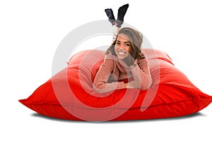 Pretty woman lying on red square shaped beanbag sofa isolated on