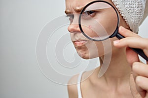 pretty woman with a magnifying glass in hand skin problems close-up