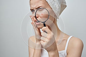 pretty woman with a magnifying glass in hand skin problems close-up