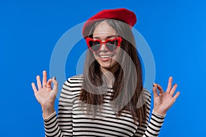 Pretty woman makes hand sign okay, ok gesture. Happy teen girl, correct perfect choice, great deal, blue background