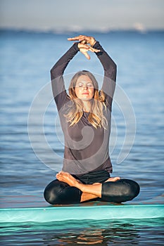 Pretty woman in meditation after her SUP Yoga on the water photo