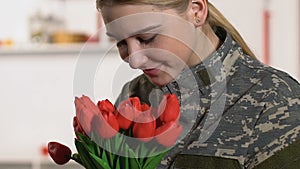 Pretty woman military uniform sniffing tulips bouquet, veterans day, patriotism