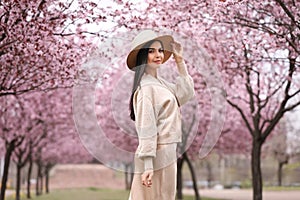 Pretty woman in park with blooming trees. Spring look