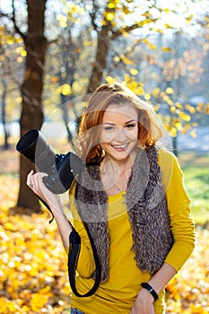 Pretty woman in the park with photocamera in the autumn day