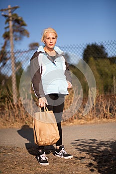 Pretty woman on a path holding bag