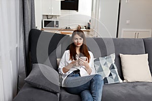 pretty woman with a phone in her hands sitting at home in an apartment interior