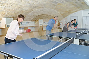 Pretty woman playing ping-pong with friends