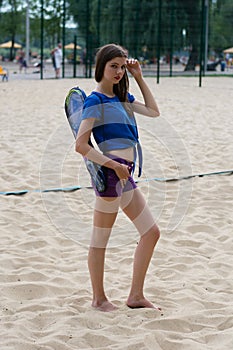 Pretty woman posing with badminton set on the sand at the beach