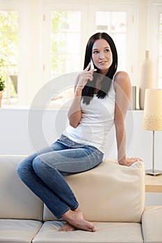 Pretty woman posing on couch with cellphone