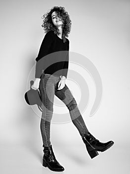 Pretty woman posing in denim pants and boots and black hat