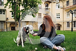 Pretty woman posing and hugging dalmatian dog on street city background