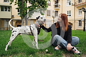 Pretty woman posing and hugging dalmatian dog on street city background